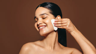 Happy young woman massaging her face with a gua sha stone