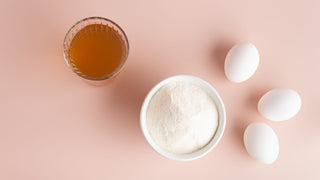 Bone broth in cup and collagen powder in bowl on pink surface