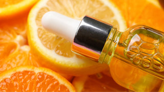 Bottle with Vitamin C Serum on Slices of Citrus Fruits