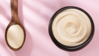 Collagen peptide powder in bowl and spoon on pink background