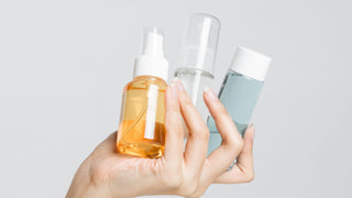 Female Hand Holding Different Cosmetic Bottles