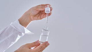 Female hands hold a cosmetic serum with a dropper.