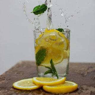 Photo of Lemon Splashing in Drinking Glass With Water