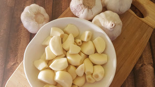 Peeled garlic cloves in bowl on cutting board