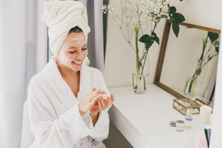 Woman sitting at a vanity and putting cream on her face