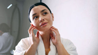 young woman wearing bathrobe looking in mirror in bathroom